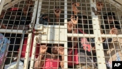 ARCHIVO: Un niño permanece junto a otras personas detenidas para ser deportadas hacia Haití, en un camión policial, en un puente que conecta a Dajabón, República Dominicana, con Haití, el 18 de marzo de 2024. 