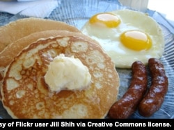 A breakfast of pancakes, eggs, and sausage.