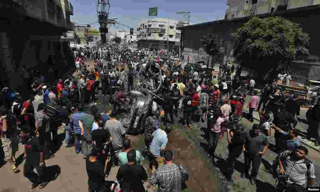 Falastinliklar Isroil havo hujumida nishonga olingan va vayron qilingan mashina qoldiqlarini ko'zdan kechirmoqda, G'azo, 8-iyul, 2014-yil.