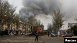 Police officers block a road as smoke rises above buildings following shelling in the course of the Russia-Ukraine war in Donetsk, Russian-controlled Ukraine, on Dec. 21, 2023.