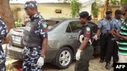 Policemen stand at the scene of a bomb blast at the public health college in northern Nigerian city of Kano, June 23, 2014.