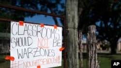 FILE - A sign asking for a change hangs on a fence near Robb Elementary School in Uvalde, Texas, June 3, 2022.