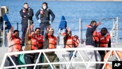 Migrants wave and give the v-sign as they disembark at Hay Wharf, Pieta, Malta, Jan. 9, 2019. 