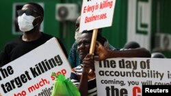 People hold signs as Ghanaians gather in the streets on the second day of protests over recent economic hardships, in Accra, Ghana, June 29, 2022.