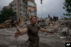 Pripadnica ukrajinskih oružanih snaga nalaže novinarima da se pomere dalje pod mesta ruskog raketnog udara na stambenu zgradu u Časiv Jaru, region Donjetska, Istočna Ukrajina, 10. jula 2022.