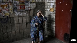 An elderly woman sits at the entrance of an apartment building in the city of Lysychansk at the eastern Ukrainian region of Donbas on June 14, 2022, amid Russian invasion of Ukraine. The cities of Severodonetsk and Lysychansk, which are separated by a riv