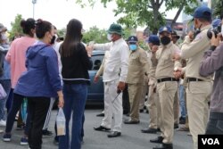 អាជ្ញាធរ​ឈរ​កាន់ដៃគ្នា​ដើម្បី​រារាំង​ក្រុមបាតុករ​មិនឱ្យ​ដើរទៅ​មុខបន្ត​ទៀត នៅ​សួនវត្តបទុម រាជធានី​ភ្នំពេញ ថ្ងៃទី១ ខែកក្តដា ឆ្នាំ២០២២។ (ហាន ណូយ/វីអូអេ)