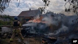 Seorang petugas pemadam kebakaran menyiram sebuah rumah serangan udara Rusia menghantam daerah perumahan, di Konstantinovka, Ukraina timur (foto: dok). 