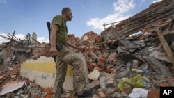 A Ukrainian soldier looks at the rubble of a school destroyed a few days ago during a missile attack, outside Kharkiv, Ukraine, on July 5, 2022. (AP Photo/Andrii Marienko)