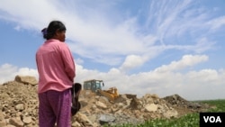 រូបឯកសារ៖ ស្ត្រី​ម្នាក់​កំពុង ​ឈរ​សម្លឹង​មើល​គ្រឿង​ចក្រ​ចាក់​ថ្ម​ចូល​បឹង​តាមោក ក្នុង​សង្កាត់​សំរោង​ត្បូង​ ​ខណ្ឌ​ព្រែកព្នៅ​ ​រាជ​ធានី​ភ្នំពេញ ថ្ងៃទី​២៧ ខែ​មិថុនា ឆ្នាំ២០២២។​ (ហាន ​ណូយ/វីអូអេ)