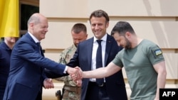 Ukrainian President Volodymyr Zelensky (R) shakes hands with Germany's Chancellor Olaf Scholz (L) next to France's President Emmanuel Macron prior to their meeting in Kyiv, on June 16, 2022.