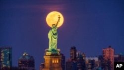 In this March 9, 2020, file photo, the full moon rises behind the Statue of Liberty in New York. (AP Photo/J. David Ake, File)