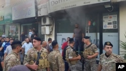 Lebanese soldiers gather outside a damaged mobile shop after what is believed to be the result of a walkie-talkie exploding inside it, in the southern port city of Sidon, Lebanon, Sept. 18, 2024.