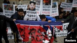 Protesters tear a defaced North Korean flag during an anti-North Korean rally in central Seoul, South Korea, Nov. 23, 2015. In the wake a group defection by 13 North Koreans, South Korea has warned its citizens of a hightned threat of abductions by