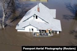 Lanni Bailey and a team from Muddy Paws Second Chance Rescue enter a flooded house to pull out several cats during the flooding of the Missouri River near Glenwood, Iowa, March 18, 2019.