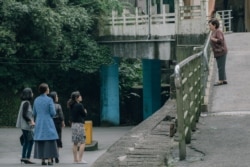 饰演秀英阿嬷的陈淑芳（右）向穿着青蓝色大衣的死去丈夫的情人（丁宁饰）喊了一声：“蔡小姐！”（威视电影授权提供）