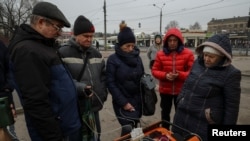 Жителі Харкова заряджають мобільні телефони від генератора на вулиці під час відключення електроенергії після того, як російські ракети вразили цивільну інфраструктуру. У ніч на 9 березня Росія обстріляла 10 регіонів України. Харків, 9 березня 2023 р. REUTERS/Софія Гатілова