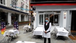 Kamarieri i një restoranti të rihapur në Londër në pritje të klientëve