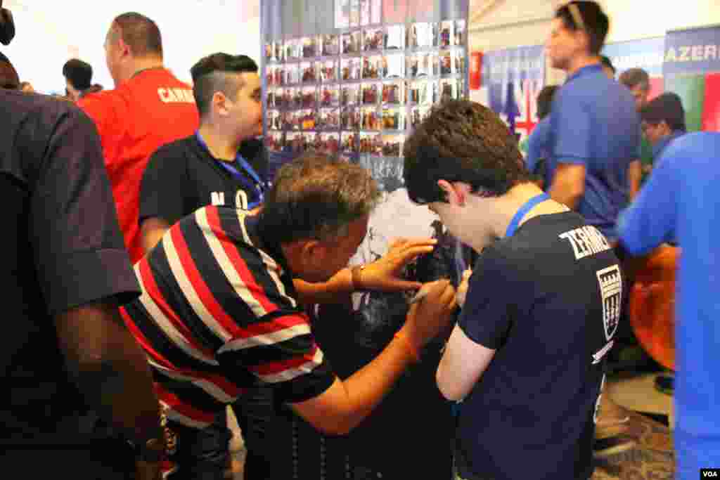 Ung Savy, Country Director &amp; Superintendent of Caring For Cambodia, signs on a poster of the Mexican robotics team after the closing of the First Global Challenge robotics competition in Washington, DC, Tuesday, July 18, 2017. (Nem Sopheakpanha/VOA Khmer)
