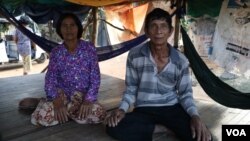 លោក ចេក ឈុន និង​អ្នកស្រី ហ៊ុល វន់ ជា​ឪពុក​ម្តាយ​របស់​លោក ឈុន វាន អង្គុយ​នៅ​លើ​គ្រែ​ខាងមុខ​ផ្ទះ ក្នុង​ភូមិ​តាប៉ោ ឃុំ​ក្តីរុន ស្រុកពួក ខេត្តសៀមរាប​ផ្ទះ។ (ស៊ុន ណារិន/VOA)