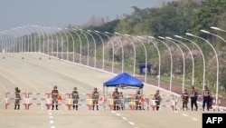 Soldiers stand guard on a blockaded road to Myanmar's parliament in Naypyidaw, Feb. 1, 2021, after the military detained the country's de facto leader Aung San Suu Kyi and the country's president in a coup.