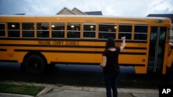 Rachel Adamus waves goodbye to her two children, Paul and Neva, as they ride the bus on the first day of school on Monday, August 3, 2020, in Dallas, Georgia, USA. (AP Photo/Brynn Anderson)