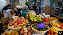 Claudia Montenegro, left, talks with Elizabeth Shoemaker at Porchlight Community Service food pantry in May. (AP Photo/Gregory Bull)