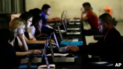 FILE - In this May 19, 2017, file photo, job seekers work on their resumes during the Opportunity Fair and Forum employment event in Dallas. 