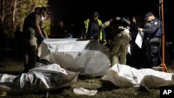 FILE - Ukrainian policemen inspect the bodies of persons that were killed by a Russian rocket attack that killed 51 people in the village of Hroza near Kharkiv, Ukraine, Oct. 5, 2023.