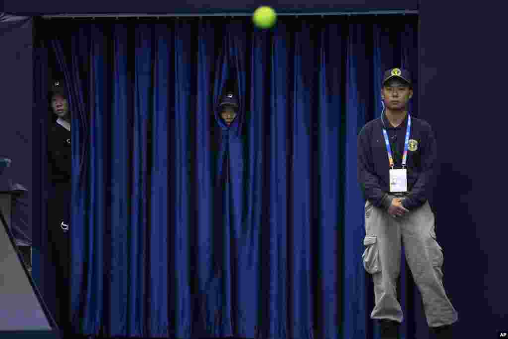 Workers peep through curtains to watch a match between France's Gael Monfils and Russia's Daniil Medvedev during the China Open tennis tournament held at the National Tennis Center in Beijing.