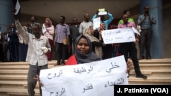 Susana Abdalla Hassan, mfanyakazi wa Benki ya Khartoum, akishikilia bango lenye kuunga mkono mapinduzi wakati wakifanya mgomo nje ya soko la bidhaa la Al-Waha mall, Khartoum, Sudan, Mei 28, 2019.