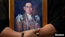 FILE - A mourner holds a portrait of Thailand's late King Bhumibol Adulyadej in Bangkok, Thailand, Oct. 14, 2016. 