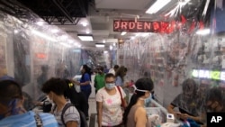 Compradores con mascarillas llenan una tienda de tecnología equipada con láminas de plástico usadas como cortinas protectoras, en Caracas. Junio 5 de 2020.