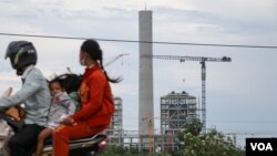 រូបឯកសារ៖ គ្រួសារមួយធ្វើដំណើរតាមម៉ូតូកាត់ការដ្ឋានសំណង់អគារខ្ពស់ស្កឹមស្កៃ នៅខេត្តព្រះសីហនុ កាលពីថ្ងៃទី ៥ ខែតុលា ឆ្នាំ ២០២១។ (ស៊ុន ណារិន/វីអូអេ)