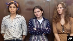 Pussy Riot members, from left, Nadezhda Tolokonnikova, Yekaterina Samutsevich and Maria Alekhina sit in a glass cage at a court room in Moscow, Russia, August 3, 2012.