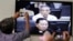 FILE - Journalists take photographs of a television screen showing the trial of Kaing Guek Eav, alias Duch, former chief of the S-21 prison, at the Extraordinary Chambers in the Courts of Cambodia (ECCC) on the outskirts of Phnom Penh, Feb. 3, 2012.