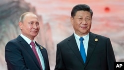 Chinese President Xi Jinping, right, and Russian President Vladimir Putin pose for a photo at the Shanghai Cooperation Organization (SCO) Summit in Qingdao in eastern China's Shandong Province, June 10, 2018.