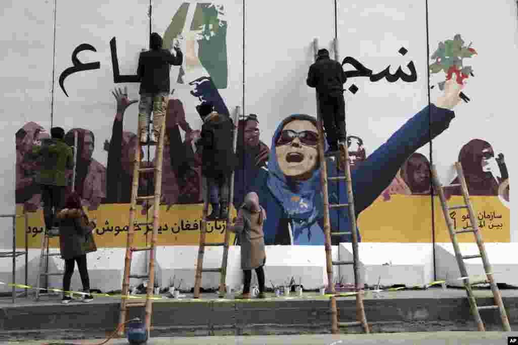 Independent Afghan artists draw a graffiti on a barrier wall of the Ministry of Women's Affairs to mark International Women's Day in Kabul, March 8, 2019.