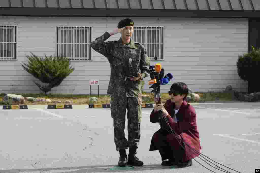 K-pop band BTS member J-Hope, center, salutes as fellow member Jin holds microphones after being discharged from a mandatory military service outside of an army base in Wonju, South Korea.