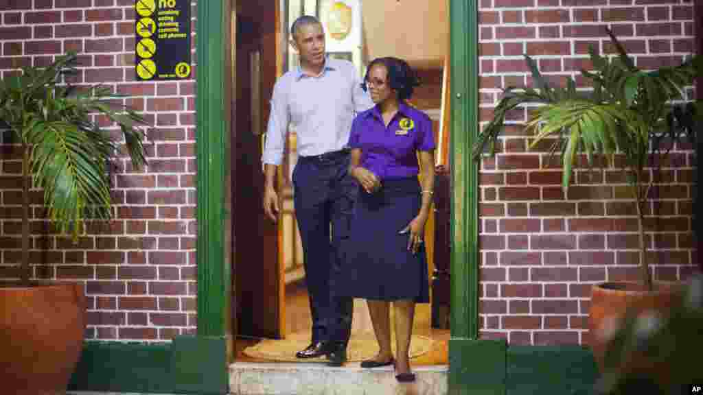Le président américain Barack Obama marche sort du musée Bob Marley avec la guide Natasha Clark, lors de sa visite à l'improviste, à Kingston, Jamaïque, le mercredi 8 Avril 2015.
