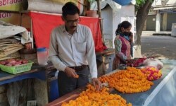 Mahesh Verma and his wife work at their flower stall outside a Hindu temple honoring the monkey god Hanuman in Lucknow, India, Friday, May 8, 2020. (AP Photo/Biswajeet Banerjee)