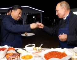 Russian President Vladimir Putin and Chinese President Xi Jinping toast during a visit to the Far East Street exhibition on the sidelines of the Eastern Economic Forum in Vladivostok, Russia September 11, 2018.