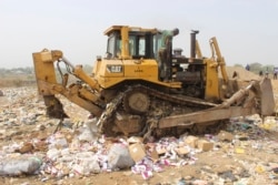 FILE - Nearly-expired COVID-19 vaccines are being destroyed by government workers in Abuja, Nigeria, Dec. 22, 2021.