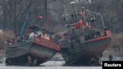 Một tàu chở hàng (phải) trên bờ sông Yalu ở Sinuiju, đối diện với thành phố biên giới của Trung Quốc Đan Đông, ngày 14 tháng 3 năm 2016.