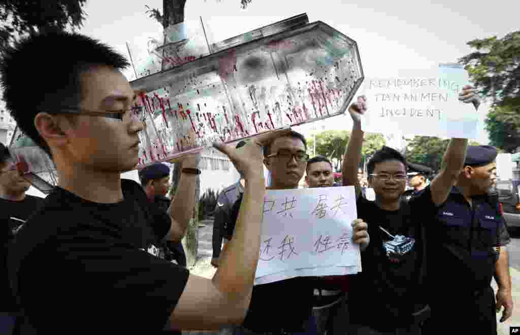 A protester holds a model of a tank covered with red paint to represent blood during a protest in front of the Chinese Embassy in Kuala Lumpur, Malaysia, June 4, 2014. 