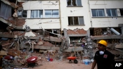 A rescue worker walks in front of an apartment building whose first four floors collapsed, in the Lindavista neighborhood of Mexico City, Sept. 20, 2017. 