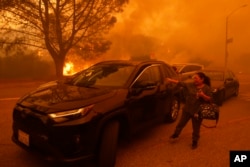 Žena plače dok bjesni požar u četvrti Pacific Palisades u Los Angelesu, utorak, 7. januara 2025. (AP Photo/Etienne Laurent)