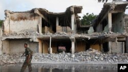 A Somali soldier walks near destroyed buildings, Feb. 27, 2016 after a suicide car bomb on Friday night in Mogadishu, Somalia. 