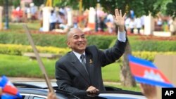 FILE-Cambodia's King Norodom Sihamoni waves from a vehicle to students during the Independence Day celebrations in Phnom Penh, Cambodia, Monday, Nov. 9, 2015.