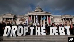 Backdropped by Britain's National Gallery in central London, protesters hold placards during a rally to show solidarity with Greece, Sunday, Feb. 15, 2015. 